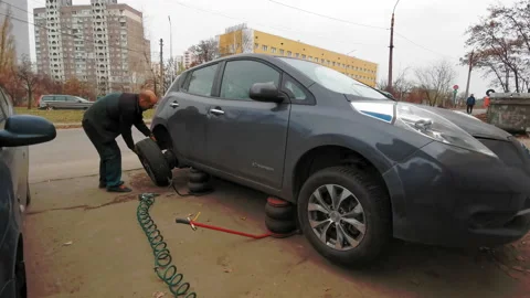 Car mechanic puts back on a wheel using a torque wrench socket on Nissan Leaf 库存影片 133732448
