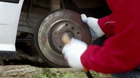 A car mechanic replacing weared disc brakes, Removing backing plates on a car Stock Footage 227158202