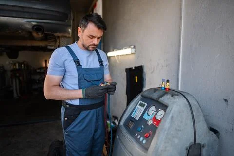 Car mechanic using air conditioning charging machine in a workshop Stock Photos