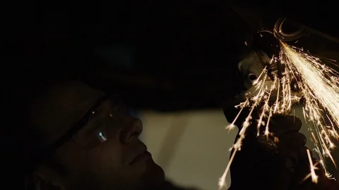 Car mechanic using an angle grinder underneath a car, in slow motion Stock Footage 102527859