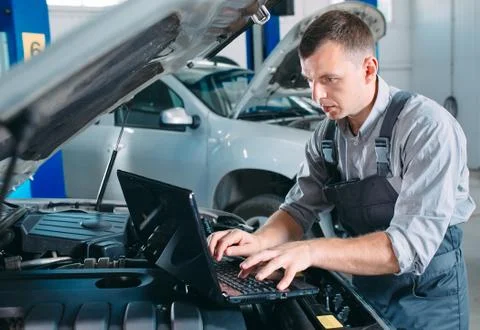 Car mechanic using a computer laptop to diagnosing and checking up on car Stock Photos