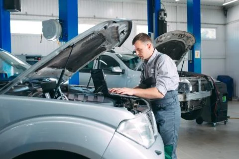 Car mechanic using a computer laptop to diagnosing and checking up on car Stock Photos