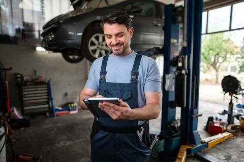 Car mechanic using a digital tablet in a auto repair shop Stock Photos
