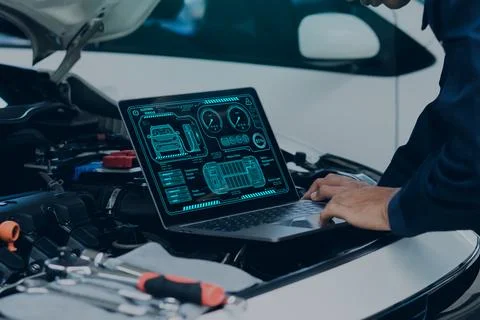 Car mechanic using laptop computer examining tuning fixing repairing car en.. Stock Photos
