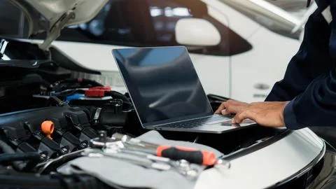 Car mechanic using laptop computer examining tuning fixing repairing car en.. Stock Photos