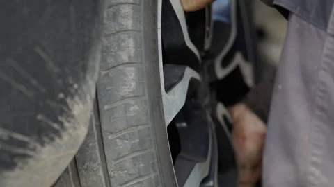 Car mechanic worker doing tire or wheel replacement with pneumatic wrench in  Stock Footage 320638588
