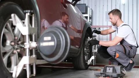 A car mechanic in a workshop attaches a jack to a car. Stock Footage 212346331