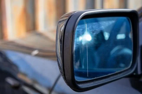 A car mirror is in focus with reflections seen in the glass. The background.. Stock Photos