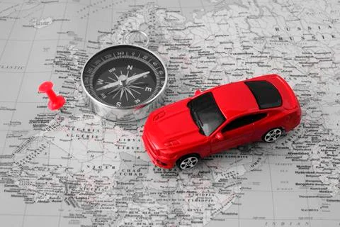 Car model, compass and mark on the world map. Car travel concept. Photos