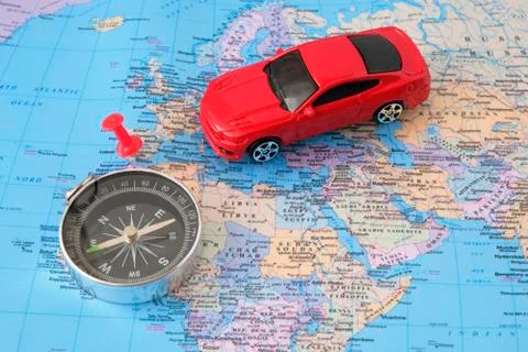 Car model, compass and mark on the world map. Car travel concept. Photos