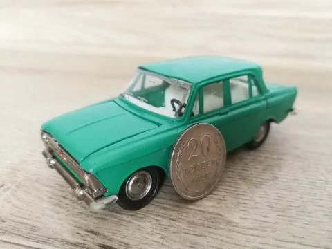 Car model toy in comparison with old coin Stock Photos