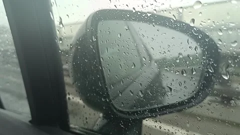 The car is in motion and raindrops are streaming down the front passenger window Stock Footage 276557979