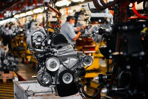 Car motor hangs on chains in assembling plant workshop Stock Photos