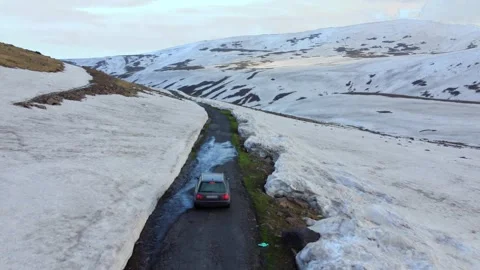 Car moves along road, making its way high in snow-capped mountains of Armenia Stock Footage 244459893
