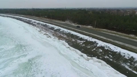 The car moves in an empty road along a frozen pond. Aerial view. Stock Footage 72512483