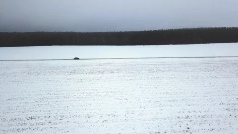 The car moves on a snowy road in the background of the forest. Winter. Bird's Stock Footage 101702503