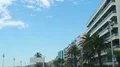Car moving down road with palm trees, expensive apartment buildings, luxury town HD Footage