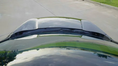Car moving with reflections of sky and green trees reflected on bonnet and glass Stock Footage 93585008