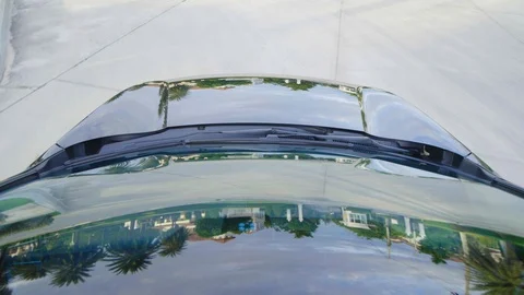 Car moving with reflections of sky and green trees reflected on bonnet and glass Stock Footage 93585064