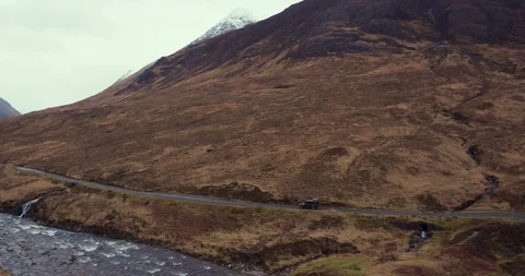 Car navigates small mountainous road with large river drone aerial 4K Stock Footage 104584050