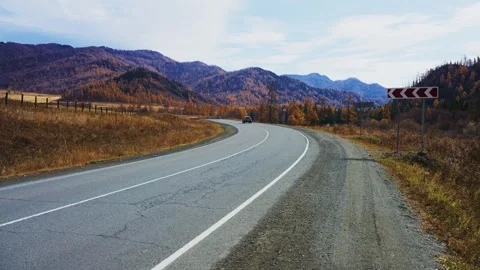 Car navigates winding mountain road during fall season Stock Footage 342734360