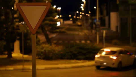 A car at night on a roundabout with a triangular traffic sign. Stock Footage 152792116
