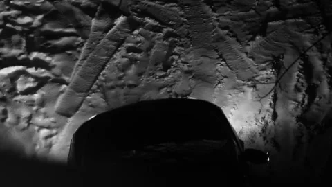 A car at night in winter with its headlights on enters and stops Stock Footage 258360717