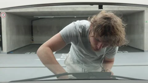 Car owner fixes an engine problem with tools in an underground parking garage Stock Footage 342924555