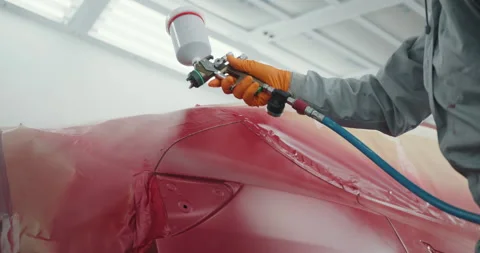 Car Painter in Protective Clothes and Mask Painting Automobile Bumper with Stock Footage 255621558
