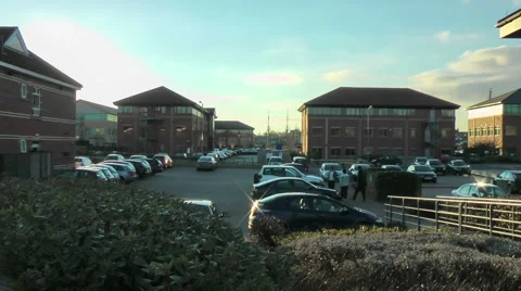 Car park between modern office blocks with masts of tall ship in distance. Stock Footage 1057922
