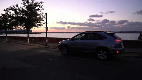 Car parked in front of water scape and sunset Stock Footage 140996038