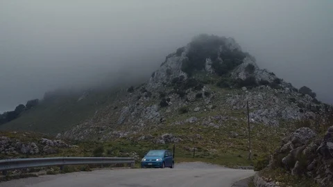 A car parked on a hill in front of a cloud covered mountain Stock Footage 88721824