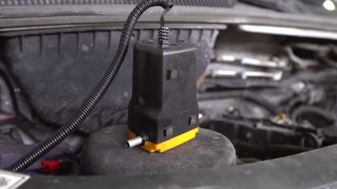 Car part resting on top of an engine with wires and nearby components, showing 스톡 동영상 330638187