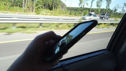 Car passenger using cell phone driving down highway close up on hand and phone Stock Footage 214201996