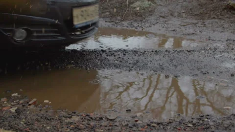 The car passes through a deep puddle. Dampness and slush on the street. Spring Vídeo Stock 105065642