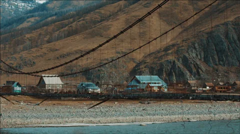 Car passes through the old suspension bridge across mountain river Stock Footage 36875053