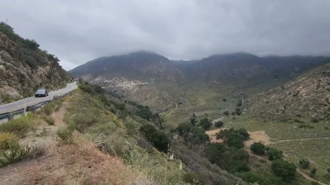 Car passing in the cliff side mountain road with a cloudy gloomy gloomy weather Stock-Footage 199547576
