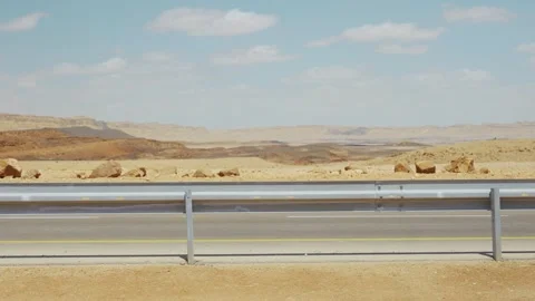 Car passing by on empty dry desolate road in desert terrain on hot summer day Stock Footage 337204211