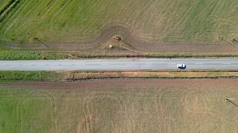 Car passing by in a road surrounded by gradient nature colors Stock Footage 240991550