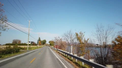 Car Passing by Tree-Lined River in Fall towards Mont-St-Hilaire, Quebec Stock Footage 224776211
