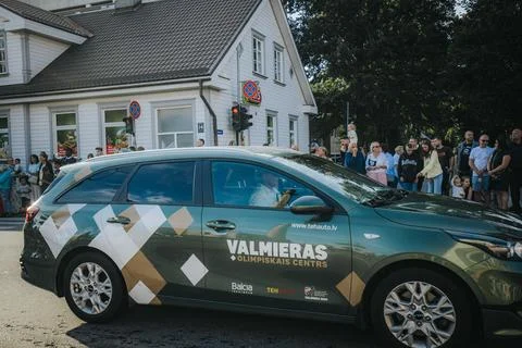 A car with patterns is moving in a procession. People are. Stock Photos