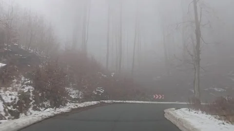 A car perspective shows a narrow mountain road in foggy late autumn with sn.. Stock Footage 323791221