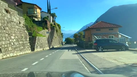 Car Point of View on Mountain Road with Alpine Lake Lugano in a Sunny Day Stockbeeldmateriaal 194011627