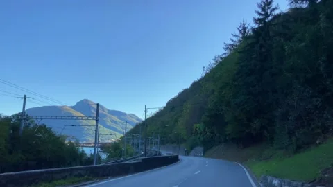 Car Point of View on Mountain Road with Lake and Mountain in a Sunny Day Stock Footage 220677270