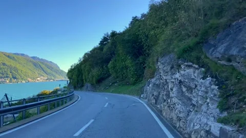 Car Point of View on Mountain Road with Lake and Mountain in a Sunny Day Stockbeeldmateriaal 220677271