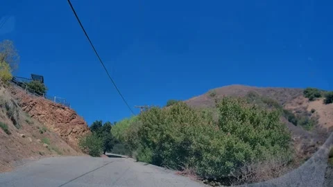 Car point of view of a mountain road past green hillsides, Los Angeles Stock Footage 343475845