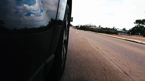 Car POV from road facing front right wheel driving down bitumen road down Stock Footage 101723001