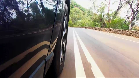 Car POV from road facing front right wheel driving down bitumen road down Stock Footage 101723011