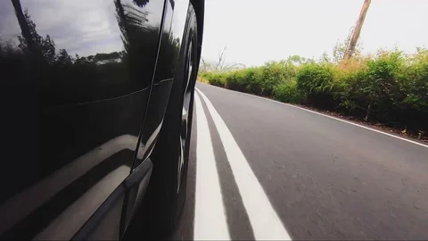 Car POV from road facing front right wheel driving down bitumen road down Stock Footage 101723028