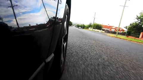 Car POV from road facing front right wheel driving down bitumen road down Stock Footage 101723036